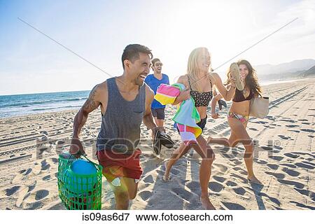 Stock Photo - Group of friends running on beach, laughing. Fotosearch