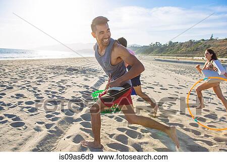 Stock Photo - Group of friends running on beach, laughing. Fotosearch