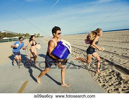 Stock Photo - Group of friends, running towards beach. Fotosearch