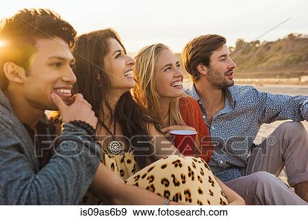 Group of friends sitting together on beach, at sunset View Large Photo Image Stock Photo - Group of friends sitting together on beach, at sunset. Fotosearch