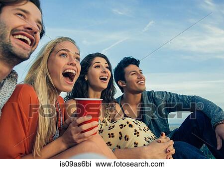 Group of friends sitting together outdoors, laughing View Large Photo Image Stock Image - Group of friends sitting together outdoors, laughing. Fotosearch