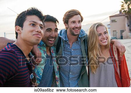Stock Photo - Group of friends standing together on beach, laughing. Fotosearch