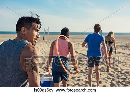 Stock Photo - Group of friends walking on beach, rear view. Fotosearch
