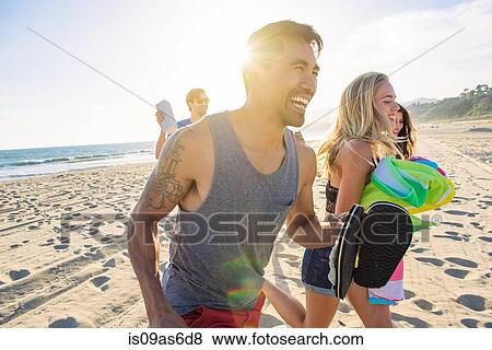 Stock Photo - Group of friends walking on beach, laughing. Fotosearch