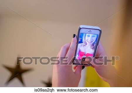 Stock Image - Hands of young woman taking smartphone selfie. Fotosearch