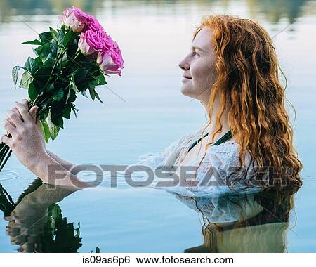 Head and shoulders of young woman with long red hair in lake gazing at bunch of pink roses View Large Photo Image Stock Photograph - Head and shoulders of young woman with long red hair in lake gazing at bunch of pink roses. Fotosearch