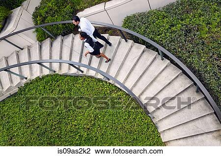 Stock Image - High angle view of business people ascending spiral stairway. Fotosearch