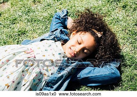 High angle view of girl lying on back on grass, hands behind head, eyes closed View Large Photo Image Stock Image - High angle view of girl lying on back on grass, hands behind head, eyes closed. Fotosearch
