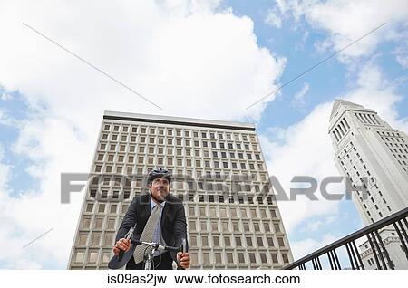 Stock Photo - Low angle view of business man cycling, Los Angeles City Hall, California, USA. Fotosearch