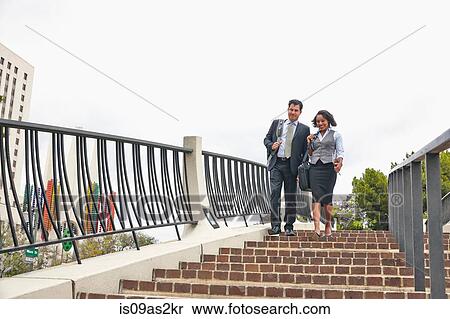 Stock Photography - Low angle view of business people descending stairway carrying briefcases on shoulder. Fotosearch