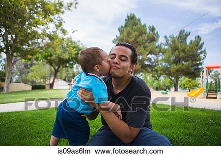 Picture - Male toddler kissing older adult brother in park. Fotosearch