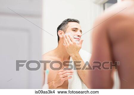Mid adult man, looking in mirror, applying shaving foam to face, rear view View Large Photo Image Picture - Mid adult man, looking in mirror, applying shaving foam to face, rear view. Fotosearch