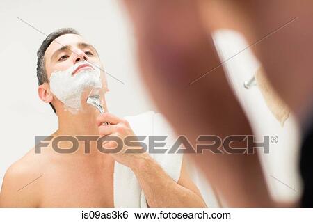 Stock Photograph - Mid adult man, looking in mirror, shaving. Fotosearch