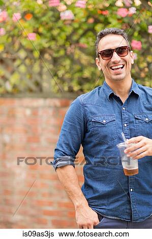 Stock Photograph - Mid adult man, outdoors, holding drink. Fotosearch