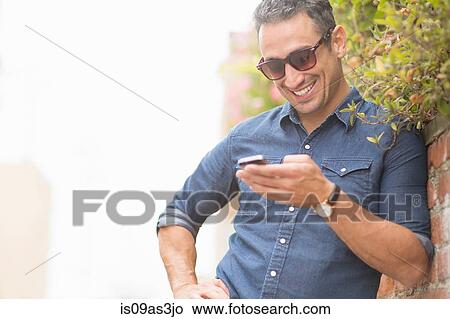 Picture - Mid adult man, outdoors, using mobile phone. Fotosearch