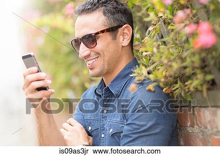 Stock Photography - Mid adult man, outdoors, using mobile phone. Fotosearch
