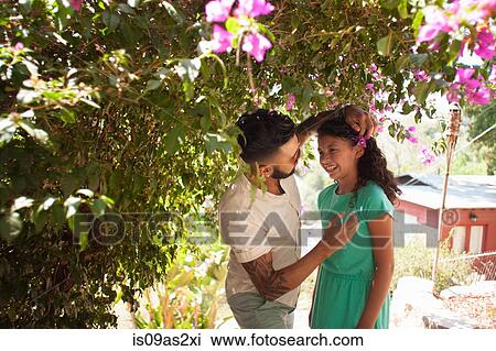 Mid adult man placing flower blossom in daughters hair View Large Photo Image Stock Image - Mid adult man placing flower blossom in daughters hair. Fotosearch