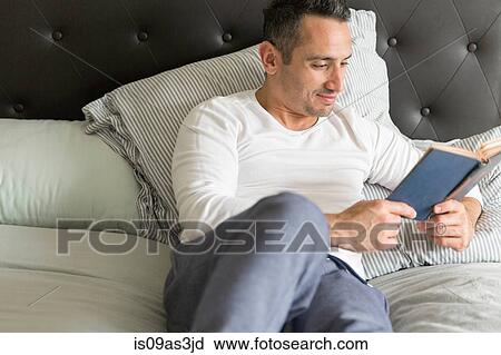 Mid adult man, relaxing on bed, reading book View Large Photo Image Stock Image - Mid adult man, relaxing on bed, reading book. Fotosearch
