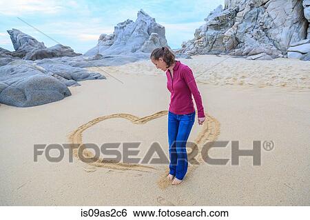 Mid adult woman on beach, drawing heart shape with feet View Large Photo Image Stock Photograph - Mid adult woman on beach, drawing heart shape with feet. Fotosearch