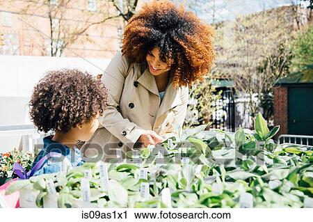 Stock Image - Mother and daughter looking at plants for sale together. Fotosearch