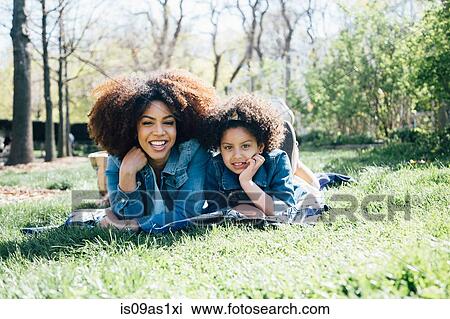 Mother and daughter lying on fronts, hand on chin, looking at camera View Large Photo Image Stock Image - Mother and daughter lying on fronts, hand on chin, looking at camera. Fotosearch
