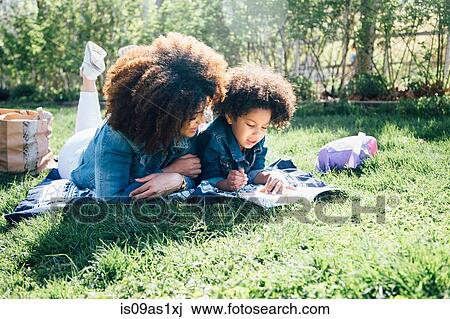 Mother and daughter lying on fronts, side by side, reading book together View Large Photo Image Stock Image - Mother and daughter lying on fronts, side by side, reading book together. Fotosearch