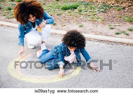 Mother and daughter using chalk to draw colourful circle on pathway View Large Photo Image Stock Image - Mother and daughter using chalk to draw colourful circle on pathway. Fotosearch