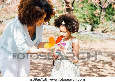 Mother helping daughter with colourful pinwheel toy View Large Photo Image Stock Photograph - Mother helping daughter with colourful pinwheel toy. Fotosearch