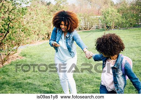 Stock Photo - Mother looking at smartphone being pulled by daughter holding hand. Fotosearch