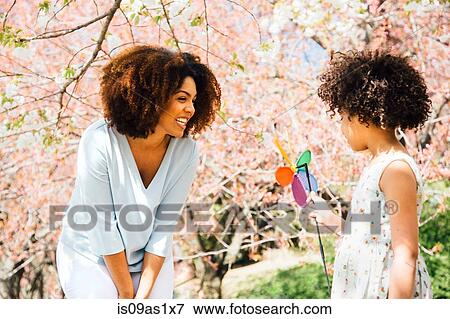 Mother smiling at daughter holding colourful pinwheel toy View Large Photo Image Stock Photo - Mother smiling at daughter holding colourful pinwheel toy. Fotosearch