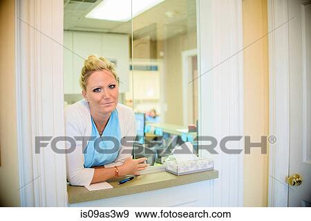 Stock Photo - Portrait of female orthodontist at dentist reception hatch. Fotosearch