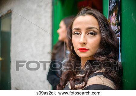 Stock Image - Portrait of glamorous sultry young woman at doorway. Fotosearch