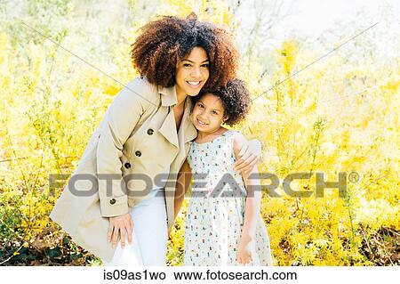 Portrait of mother with arm around daughter, looking at camera, smiling View Large Photo Image Picture - Portrait of mother with arm around daughter, looking at camera, smiling. Fotosearch