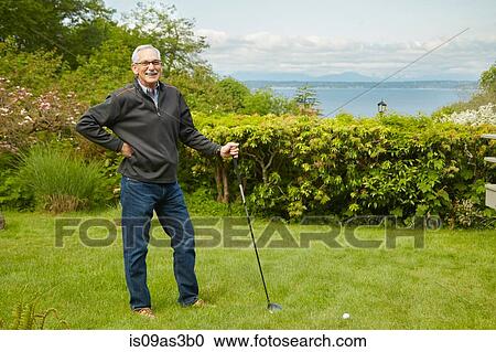 Stock Image - Portrait of senior man, holding golf club. Fotosearch