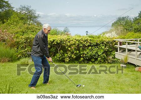 Stock Photo - Portrait of senior man, practising golf swing. Fotosearch
