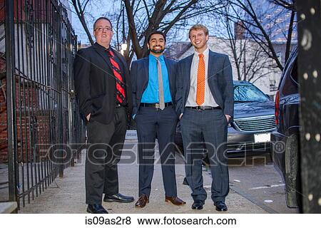 Stock Photo - Portrait of three young male friends wearing suits for night out. Fotosearch