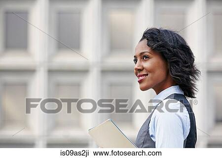 Portrait of young business woman holding paper work, looking away, smiling, side view View Large Photo Image Stock Image - Portrait of young business woman holding paper work, looking away, smiling, side view. Fotosearch