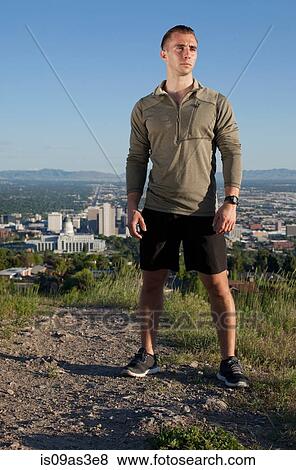 Stock Photo - Portrait of young male runner on dirt track above city in valley. Fotosearch