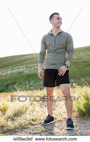Stock Image - Portrait of young male runner on hillside. Fotosearch