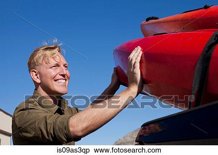 Portrait of young man unloading kayak, looking away smiling View Large Photo Image Stock Photography - Portrait of young man unloading kayak, looking away smiling. Fotosearch