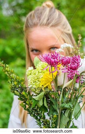 Stock Image - Portrait of young woman behind bunch of flowers. Fotosearch