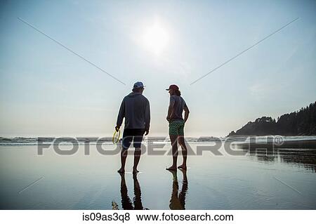 Rear silhouetted view of two young men chatting on Short Sands Beach, Oregon, USA View Large Photo Image Stock Photo - Rear silhouetted view of two young men chatting on Short Sands Beach, Oregon, USA. Fotosearch