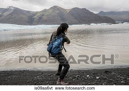 Rear view of female tourist skimming stones in sea, Skaftafell, Iceland View Large Photo Image Stock Photograph - Rear view of female tourist skimming stones in sea, Skaftafell, Iceland. Fotosearch