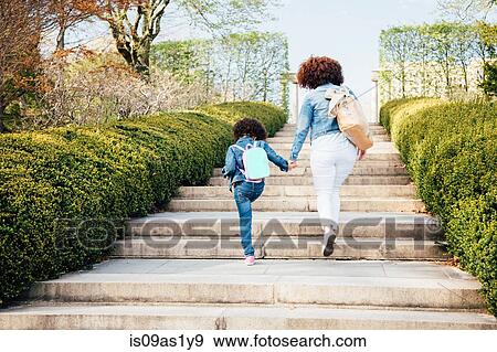 Stock Photo - Rear view of mother and daughter holding hands going up stairway. Fotosearch