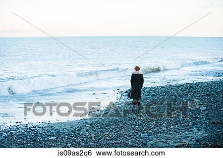 Rear view of woman strolling on beach View Large Photo Image Stock Photograph - Rear view of woman strolling on beach. Fotosearch