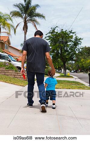Rear view of young man and toddler brother strolling along suburban sidewalk View Large Photo Image Stock Photo - Rear view of young man and toddler brother strolling along suburban sidewalk. Fotosearch