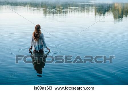Rear view of young woman in lake rippling surface with her fingers View Large Photo Image Stock Image - Rear view of young woman in lake rippling surface with her fingers. Fotosearch