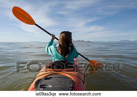 Stock Photo - Rear view of young woman kayaking, holding paddles, Great Salt Lake, Utah, USA. Fotosearch