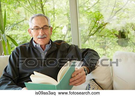 Stock Photography - Senior man at home, reading book. Fotosearch