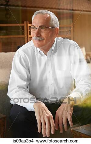 Picture - Senior man at home, sitting in chair, looking away. Fotosearch